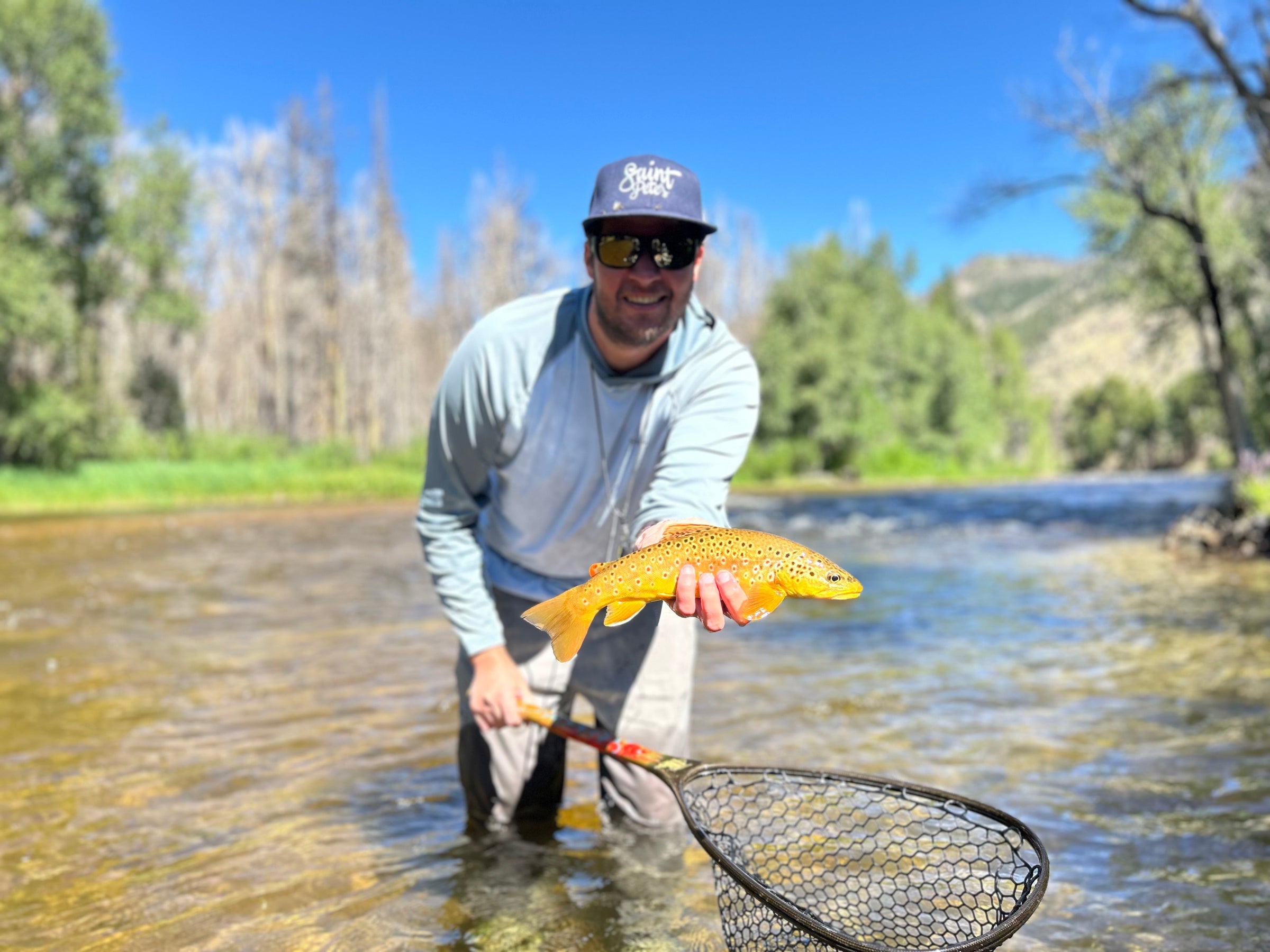 angler in water holding fish