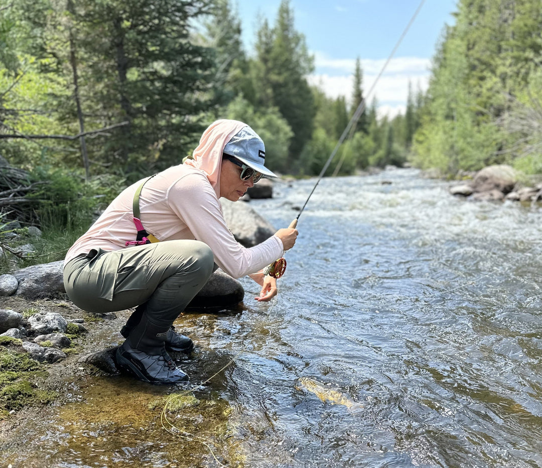 Person fly fishing in a river surrounded by trees